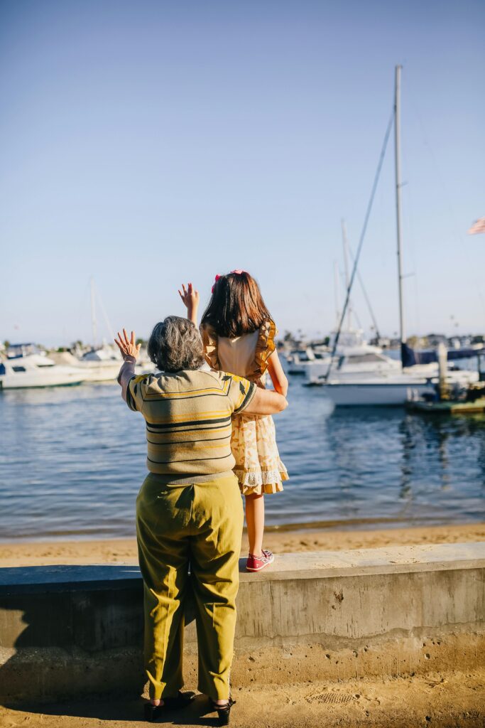 Mujer mayor y una niña saludando junto al puerto